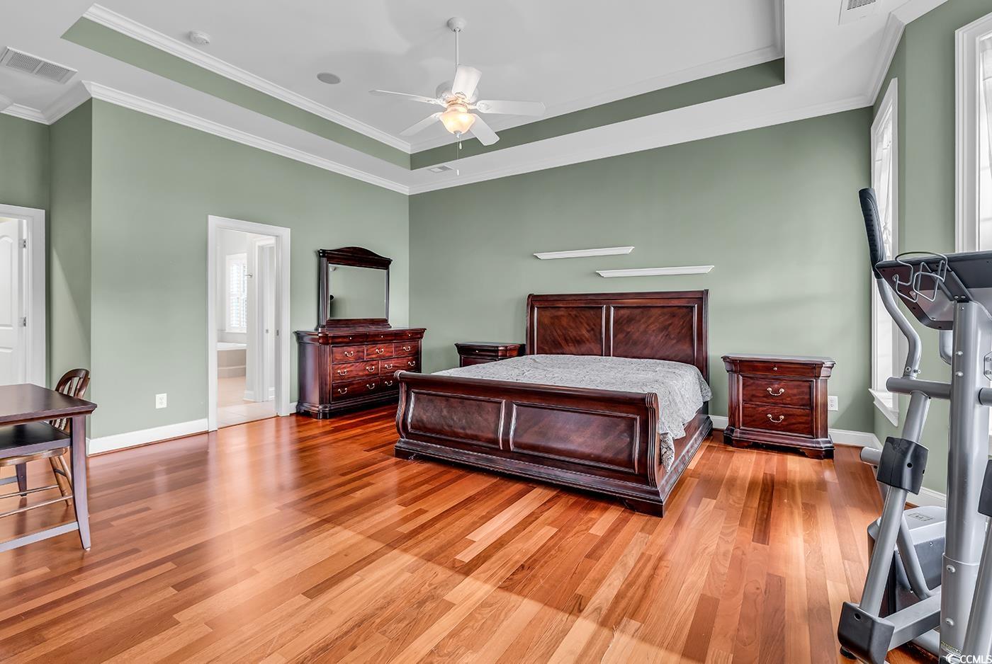 7029 Byrnes Lane Myrtle Beach, SC 29588 - Photo 18 of 40 Bedroom featuring light wood-style flooring, ornamental molding, a raised ceiling, and ensuite bath
