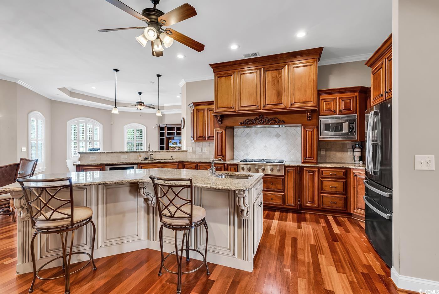 7029 Byrnes Lane Myrtle Beach, SC 29588 - Photo 8 of 40 Kitchen featuring appliances with stainless steel finishes, ceiling fan, brown cabinetry, recessed lighting, and wood finished floors