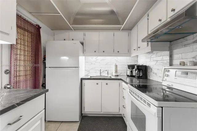 a kitchen with granite countertop white cabinets and white appliances
