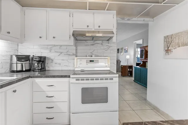 a kitchen with granite countertop white cabinets and appliances