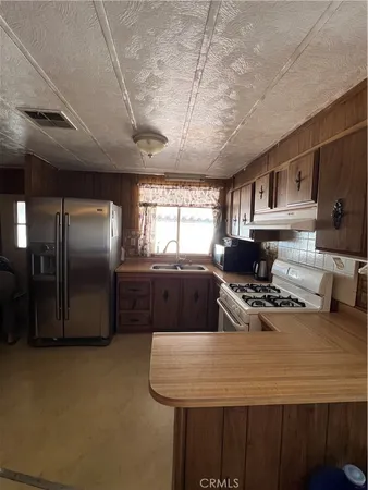 a kitchen with stainless steel appliances granite countertop a sink a stove a refrigerator cabinets and a dining table