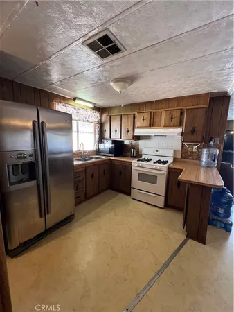 a kitchen with stainless steel appliances granite countertop a stove a refrigerator a sink a oven with white cabinets and wooden floor