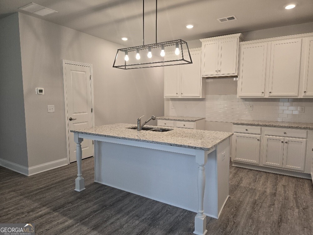 3405 Ripple Loop, Unit 127 Atlanta, GA 30349 - Photo 7 of 26 a kitchen with kitchen island granite countertop a sink cabinets and wooden floor