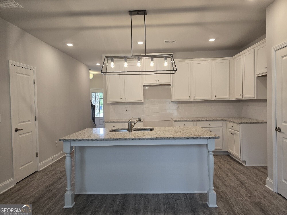 3405 Ripple Loop, Unit 127 Atlanta, GA 30349 - Photo 8 of 26 a kitchen with kitchen island granite countertop a sink cabinets and wooden floor