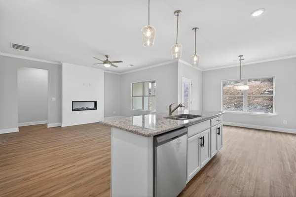 a kitchen with granite countertop a sink appliances and wooden floor