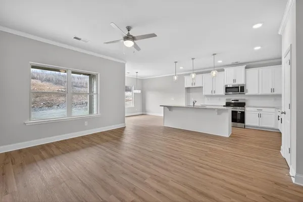 a view of kitchen with kitchen island wooden floors appliances and cabinets