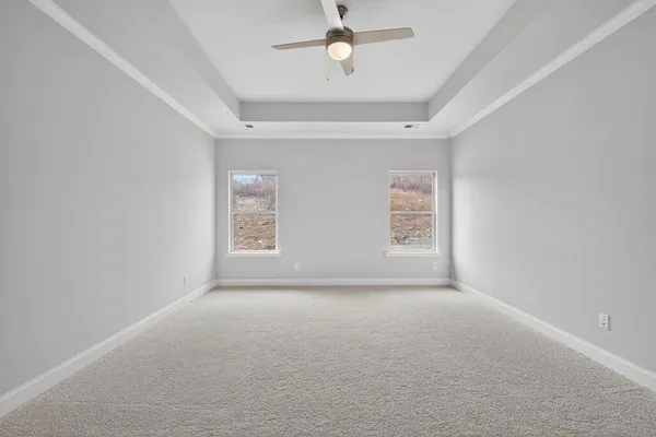 an empty room with windows and ceiling fan