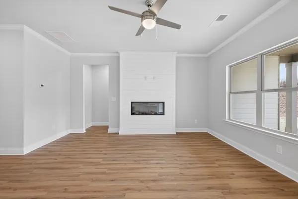 a view of an empty room with a window and wooden floor