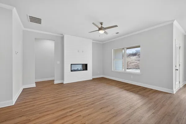 a view of an empty room with a window and wooden floor