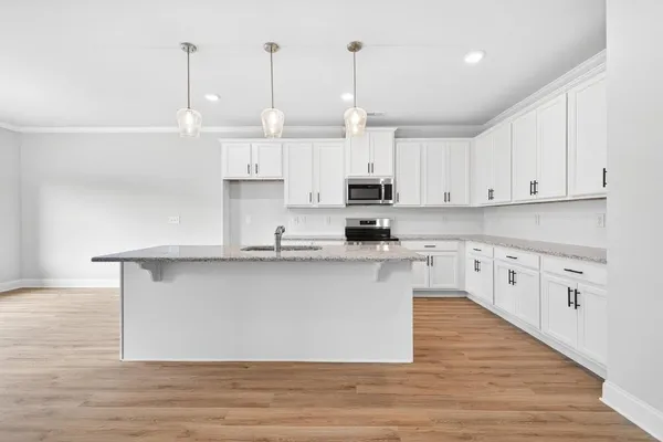 a kitchen with stainless steel appliances granite countertop a sink a stove a refrigerator and white cabinets