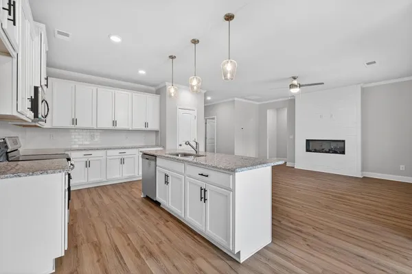 a large kitchen with kitchen island a stove a sink a refrigerator and white cabinets with wooden floor