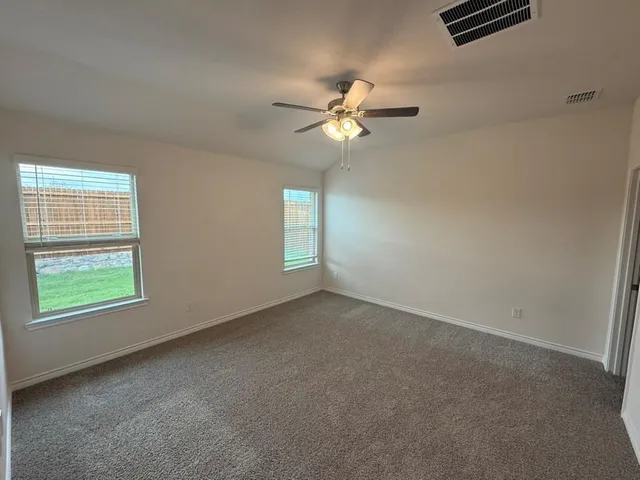 an empty room with windows and fan