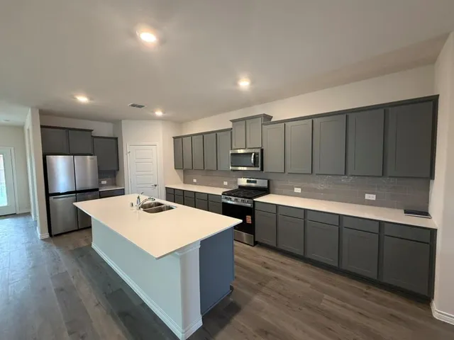 a kitchen with stainless steel appliances granite countertop a sink a stove a refrigerator and a oven