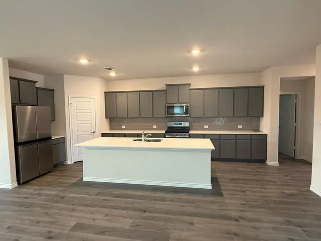 a large kitchen with kitchen island a sink a stove a refrigerator and white cabinets