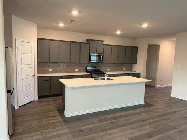a view of kitchen with stainless steel appliances granite countertop a stove a sink and a refrigerator