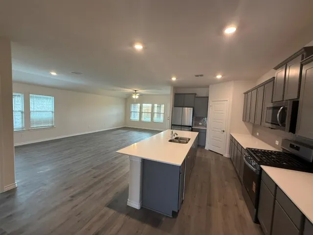 a large kitchen with stainless steel appliances a large counter top a stove a chimney a sink and a refrigerator