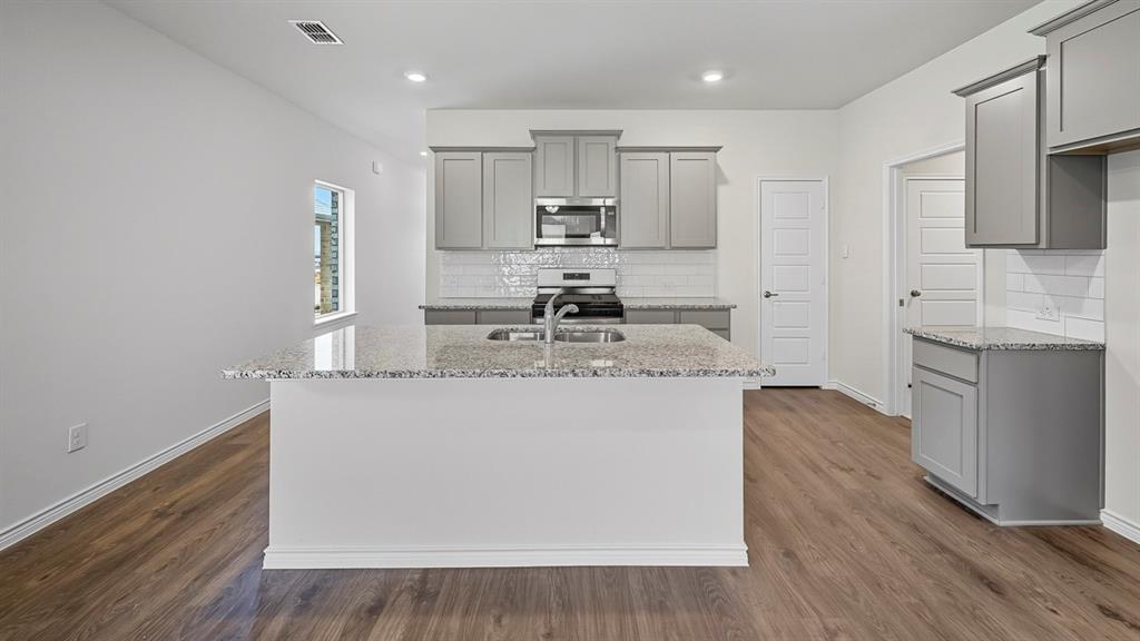 1203 Rusted Rail Drive Princeton, TX 75407 - Photo 24 of 37 Kitchen with gray cabinetry, light stone counters, backsplash, and recessed lighting