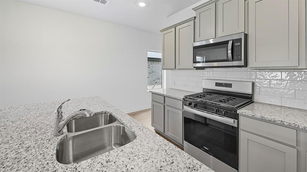 1203 Rusted Rail Drive Princeton, TX 75407 - Photo 26 of 37 Kitchen with stainless steel appliances, light stone counters, gray cabinetry, recessed lighting, and tasteful backsplash