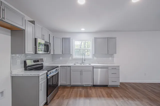 a kitchen with a sink cabinets wooden floor and stainless steel appliances