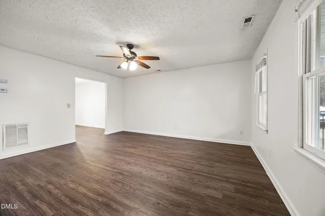 a view of an empty room with a window and wooden floor