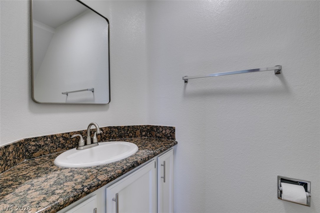 2113 Desert Peak Road Las Vegas, NV 89134 - Photo 20 of 33 This clean and functional bathroom features a single vanity with granite countertops and a sleek mirror.
