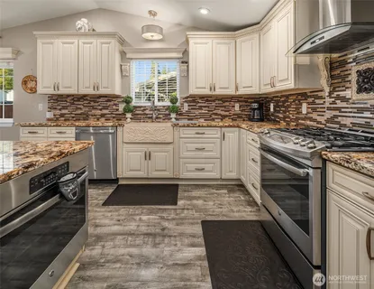 a kitchen with stainless steel appliances granite countertop a stove sink cabinets and microwave