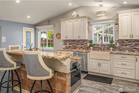 a kitchen with granite countertop a sink and white cabinets