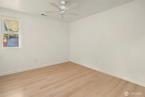 an empty room with a window and ceiling fan
