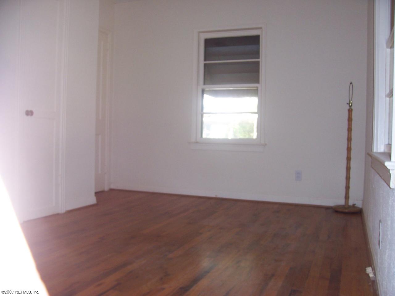 4908 Dundee Road Jacksonville, FL 32210 - Photo 9 of 16 an empty room with wooden floor and windows