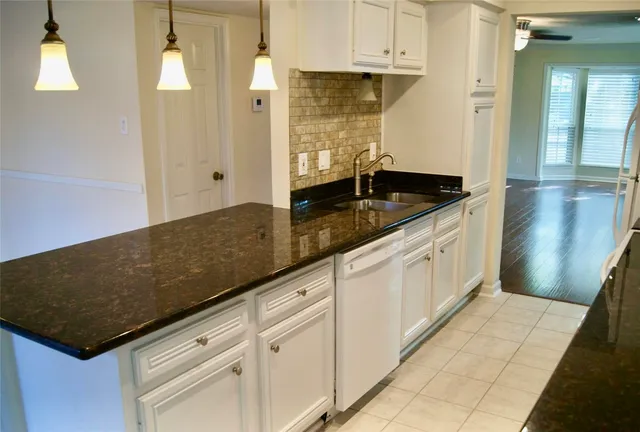 a kitchen with granite countertop a sink a stove and cabinets