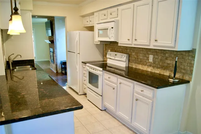 a kitchen with stainless steel appliances granite countertop a refrigerator a stove and white cabinets