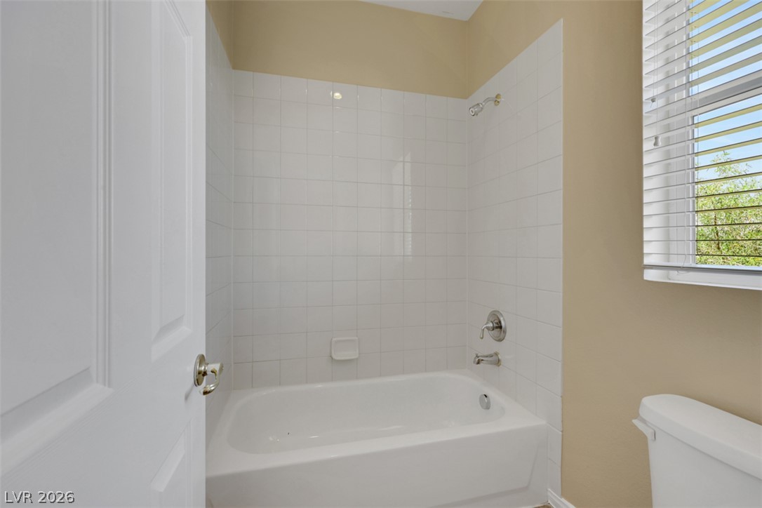 10328 Hawk Ravine Street Las Vegas, NV 89178 - Photo 33 of 55 A pristine bathtub and shower combination provides a serene space for personal care.