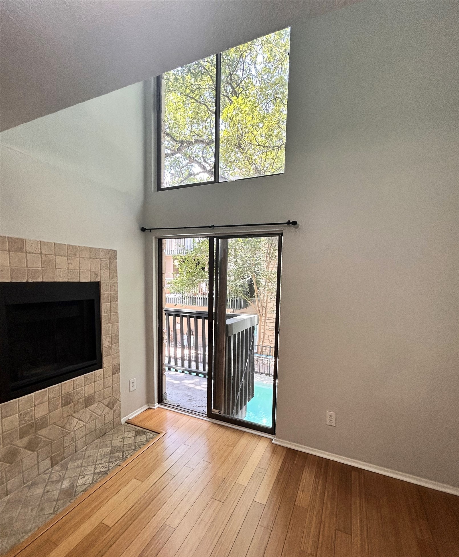 3627 Menchaca Road, Unit 204 Austin, TX 78704 - Photo 3 of 23 Tall windows and a sliding glass door illuminate a fireplace and wood flooring.
