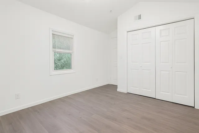 an empty room with wooden floor and windows