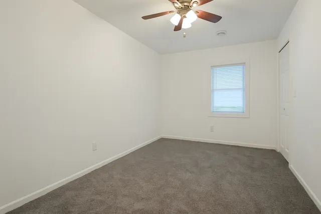 an empty room with a chandelier fan