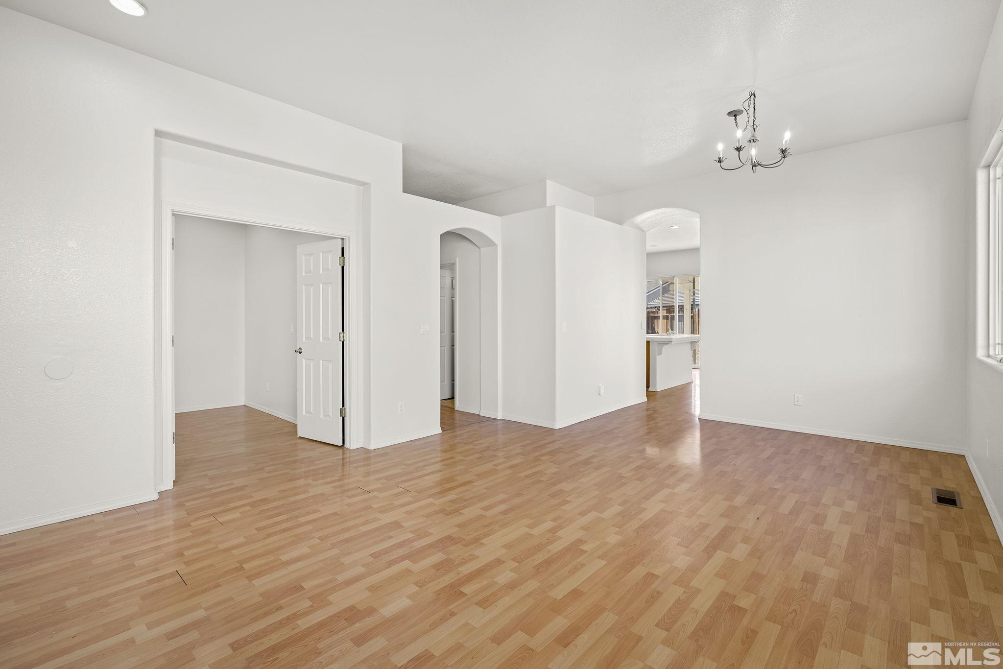 9671 Comanche Moon Drive Reno, NV 89521 - Photo 4 of 18 a view of an empty room with wooden floor and a chandelier