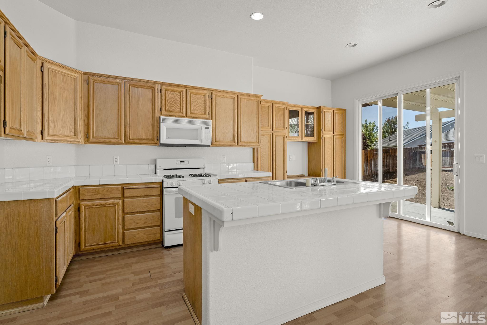 9671 Comanche Moon Drive Reno, NV 89521 - Photo 8 of 18 a kitchen with stainless steel appliances granite countertop a stove a sink and a refrigerator with wooden cabinets