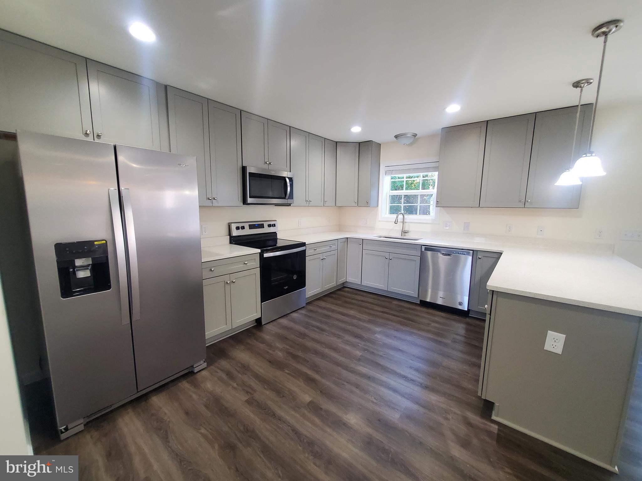 205 Cilento Drive Magnolia, DE 19962 - Photo 30 of 46 a kitchen with kitchen island granite countertop stainless steel appliances and wooden cabinets