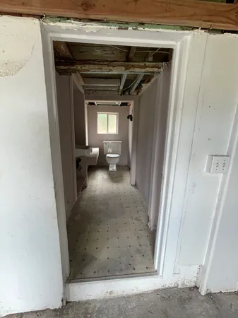 a view of a hallway with wooden floor and a living room