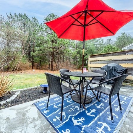 36 Atkins Road, Unit E2 Sandwich, MA 02537 - Photo 19 of 21 a view of a patio with table and chairs under an umbrella