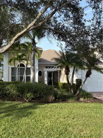 a front view of a house with a yard and potted plants