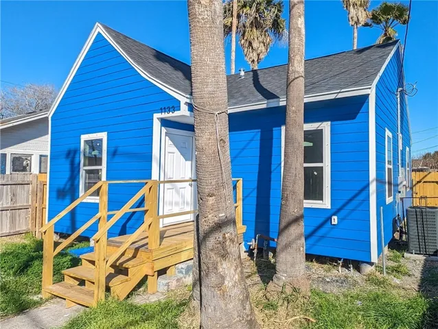 a view of wooden house with a small yard and wooden fence