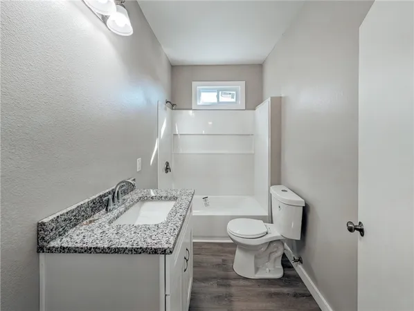 a bathroom with a granite countertop toilet a sink and a mirror