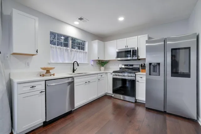 a kitchen with granite countertop white cabinets and stainless steel appliances