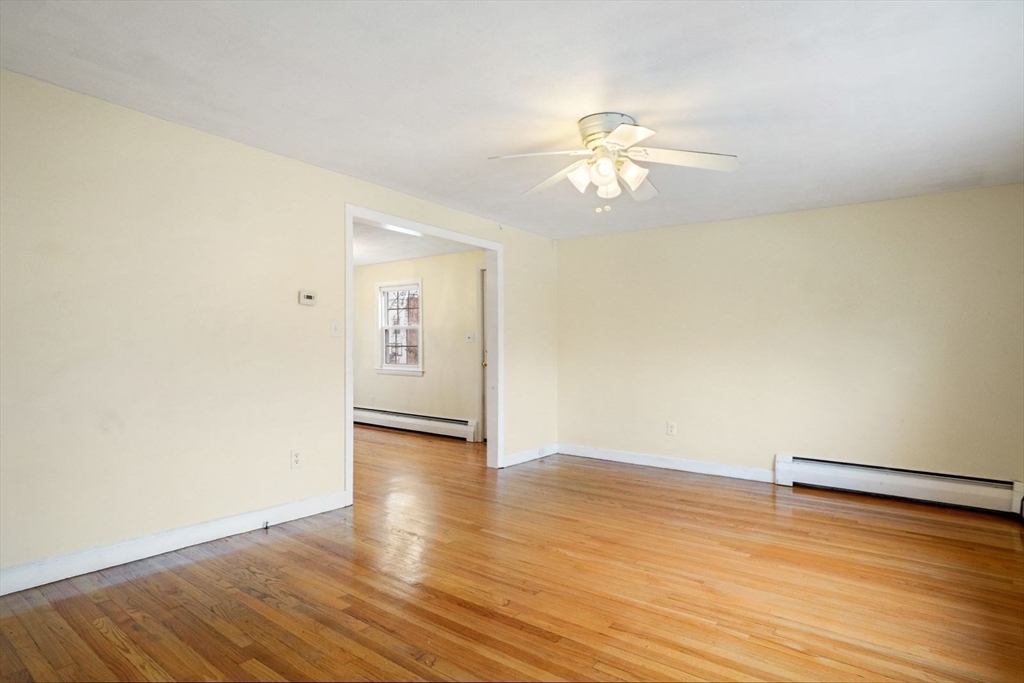 10-12 Norcross Circle Arlington, MA 02474 - Photo 11 of 31 an empty room with wooden floor chandelier fan and windows