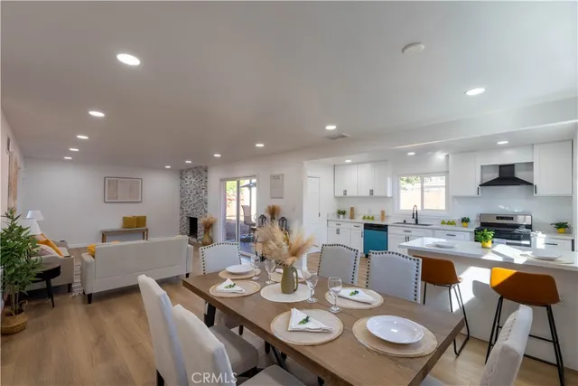 a view of a dining room and livingroom view with furniture wooden floor a rug and a chandelier