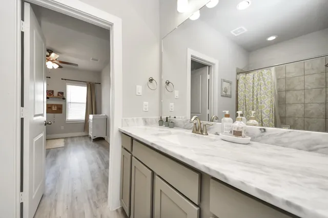 a en suite bathroom with a granite countertop sink and a mirror