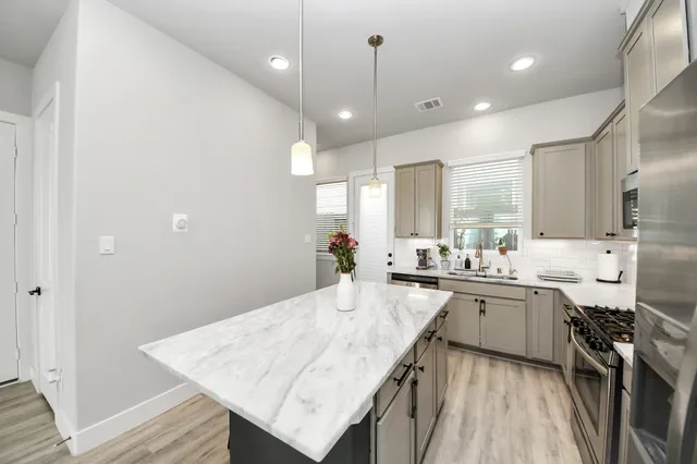 a large kitchen with lots of counter space a sink appliances and living room view