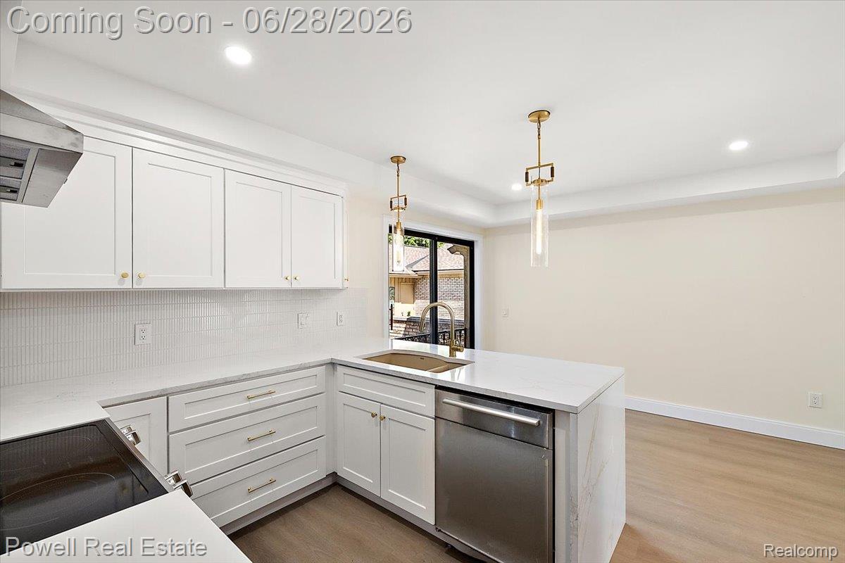 1447 Ravineview Court, Unit C12 Bloomfield Hills, MI 48304 - Photo 26 of 49 Contemporary kitchen featuring white cabinetry, a waterfall-edge island, integrated stainless steel appliances, and wood-finish flooring