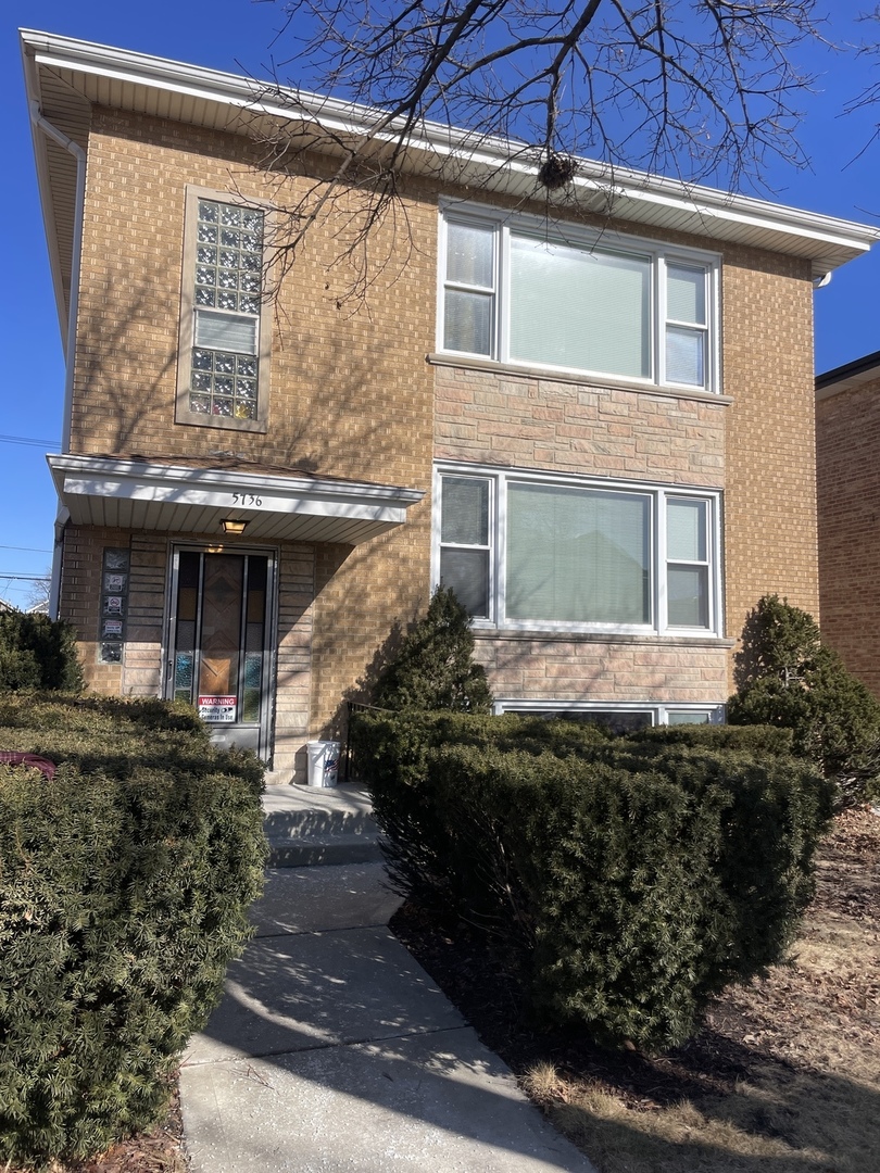 5736 West Gunnison Street, Unit 2 Chicago, IL 60630 - Photo 1 of 17 a front view of a house with a garden